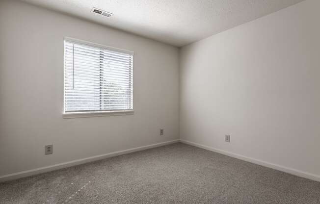 a bedroom with white walls and a window