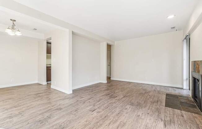 A spacious room with wooden flooring and white walls.