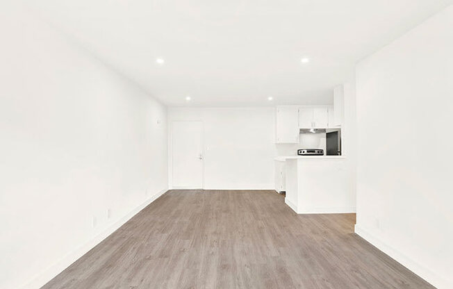 A spacious room with wooden flooring and white walls.