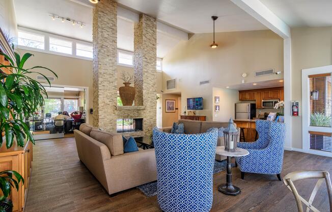 A living room with a stone fireplace and blue patterned chairs.