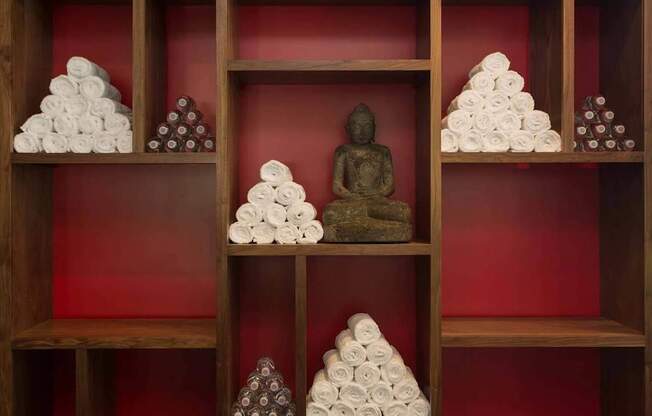 A shelf with towels and a Buddha statue.