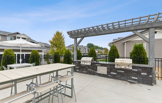 A patio with a table, chairs, and a grill.