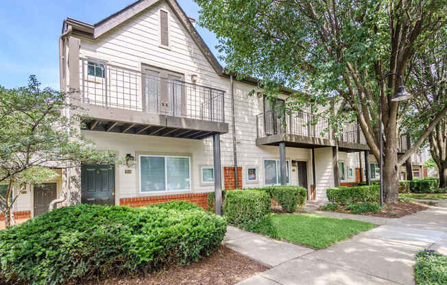 an apartment building with two balconies and a sidewalk
