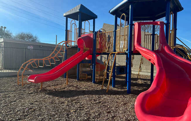 A playground with a red slide and a blue roofed structure.