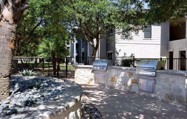 a stone wall with two barbecue grills in front of a building