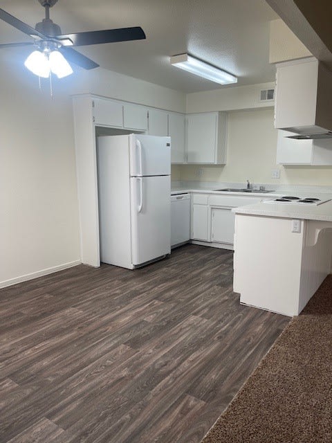 an empty kitchen with a refrigerator and a ceiling fan