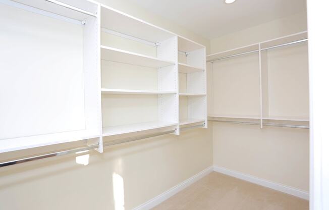 closet with light colored carpeting and white built in shelves at York House, Saint Louis, 63108