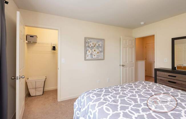 A bedroom with a patterned bedspread and a walk in closet.