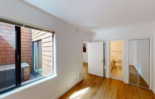 a bedroom with a large window and a door to a bathroom