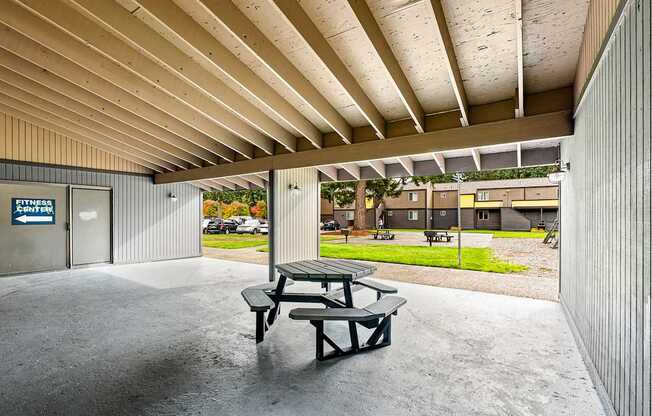 A picnic table sits under a covered patio area.