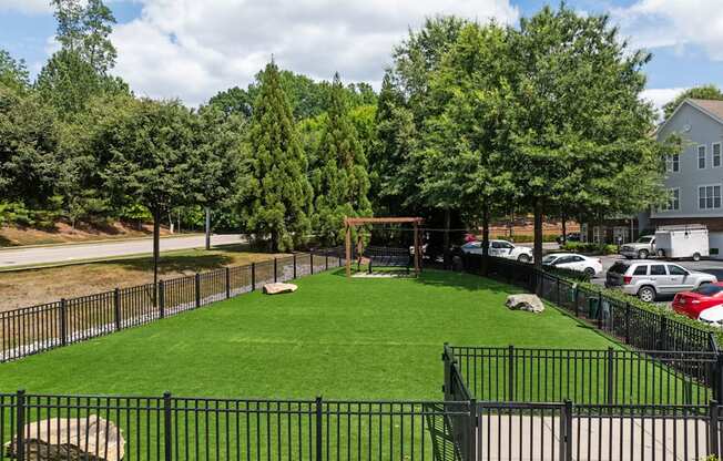 the yard is fenced off with a grass lawn and a swing set