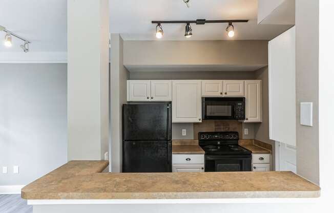 an empty kitchen with a counter top and a black refrigerator