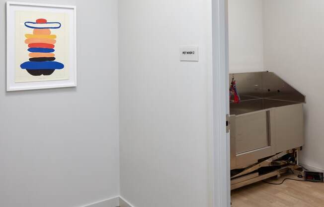 A painting of a stack of shapes is on the wall in a white room.