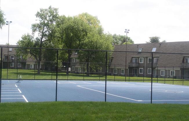 a tennis court in front of an apartment building