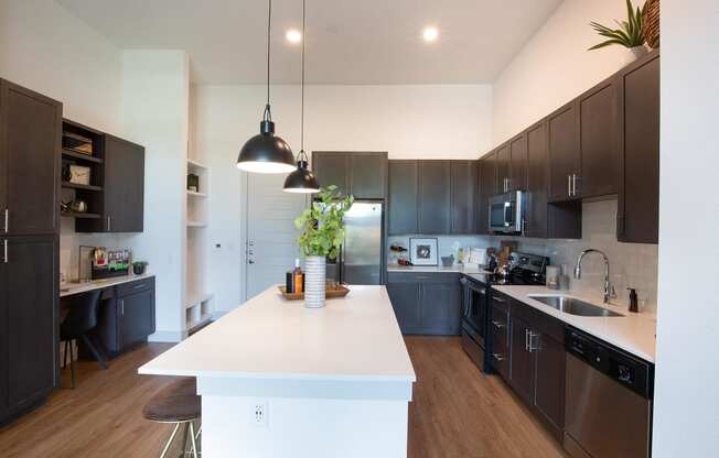 a large kitchen with a white island and dark cabinets