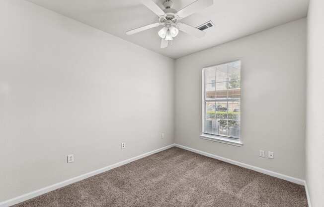 an empty room with carpet and a ceiling fan