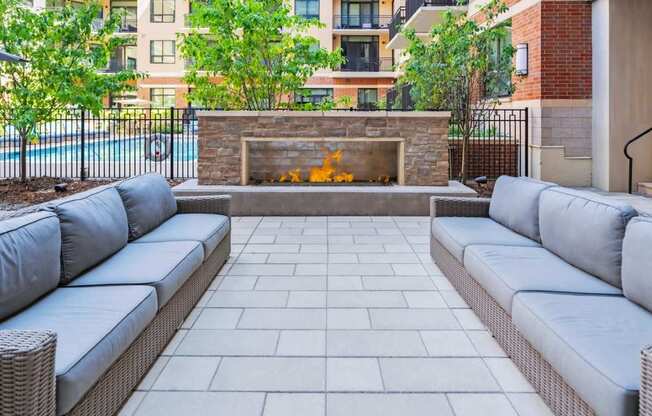 A patio with a grey couch and a fireplace.