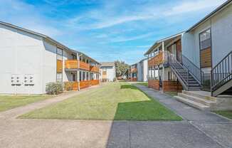 A row of modern apartment buildings with a clear blue sky above at The Marq in Shreveport, LA