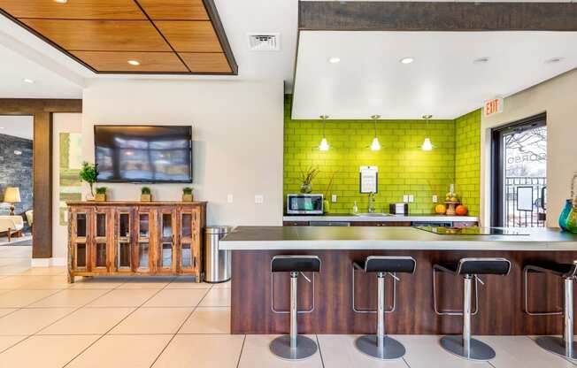 a kitchen with green tiles and a bar with stools