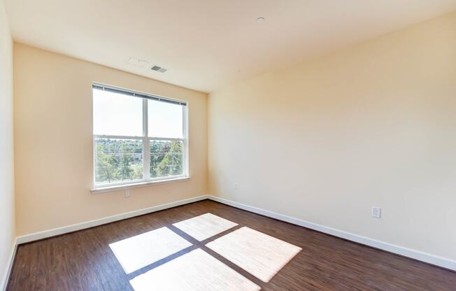 vacant living area with hardwood floors and large window at archer park apartments in Washington dc