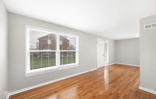 a bedroom with a large window and hardwood floors