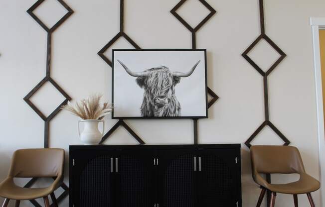 a living room with a black cabinet and a bull print on the wall