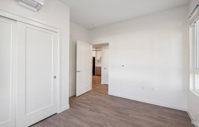 an empty bedroom with white walls and wood flooring