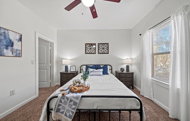 A bedroom with a bed, nightstands, and a ceiling fan.