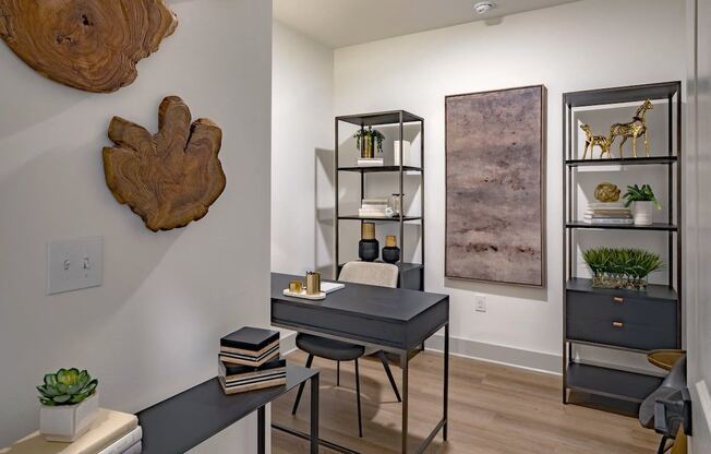a home office with a black desk and a wood piece on the wall