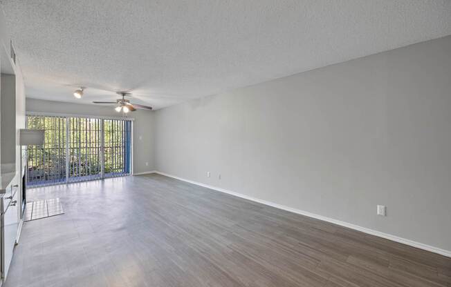 A room with a ceiling fan and sliding glass doors.