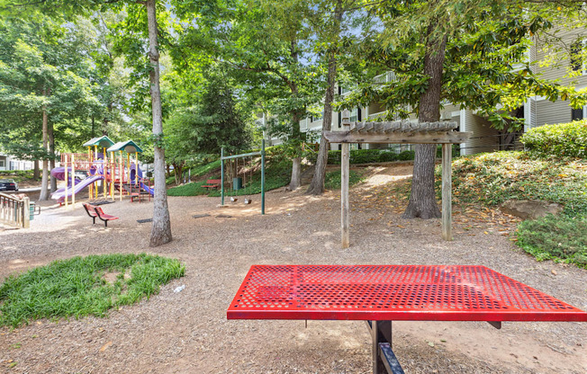 a park with a red picnic table and playground equipment