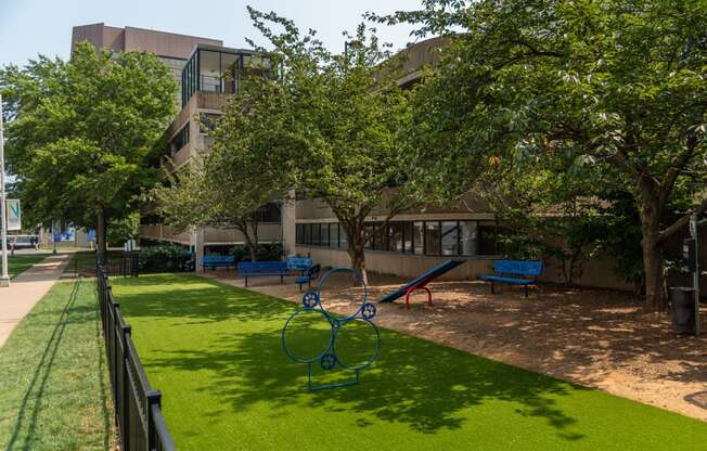 a playground with trees and benches in front of a building