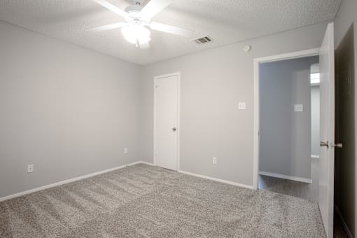 A room with a ceiling fan and carpeted floor.