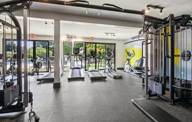 A gym with a variety of equipment including treadmills, weights, and exercise machines.