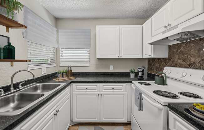 A kitchen with white cabinets and a black countertop.