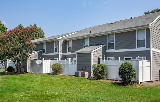a gray house with a yard and a white fence
