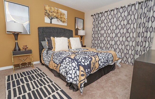 A bedroom with a patterned bedspread and a black and white rug at Magnolia apartments in Shreveport, LA