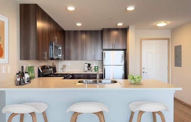 a kitchen with a counter top with three stools at Spyglass Hill Apartments, Bremerton