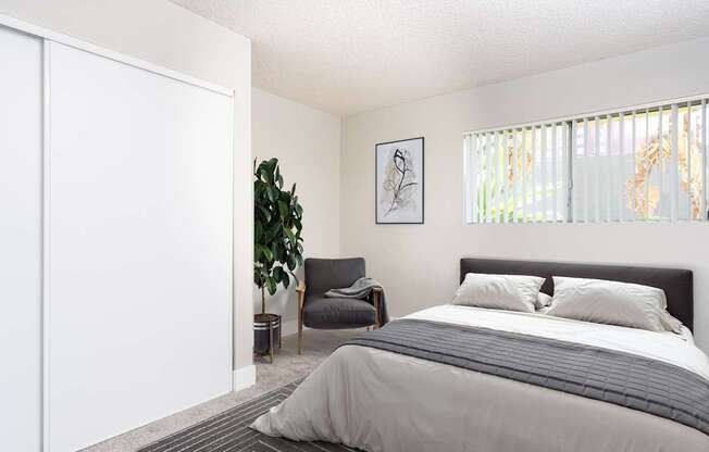 A bedroom with a large bed and a chair.