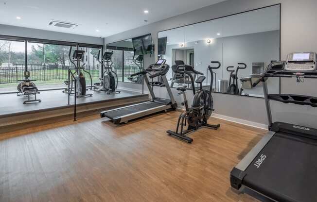 a gym with treadmills and other exercise equipment on a wooden floor