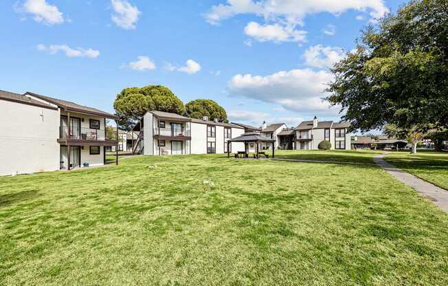A grassy field with apartment buildings in the background.