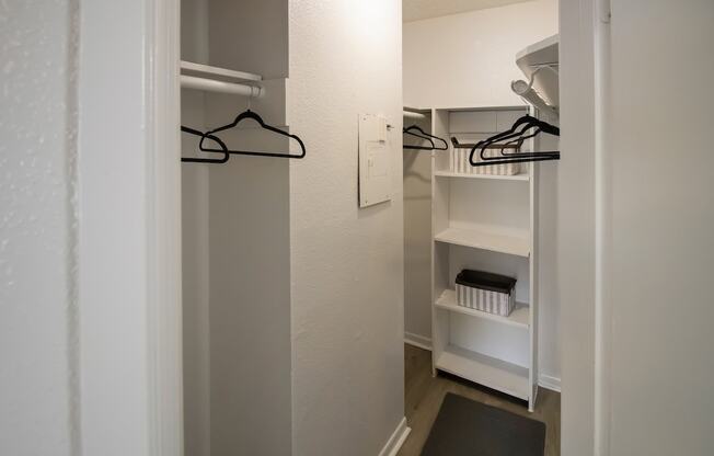 a walk in closet in a small room with white walls and black hangers on