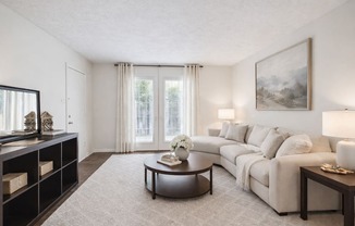 A living room with a white couch, a coffee table, and a painting on the wall.