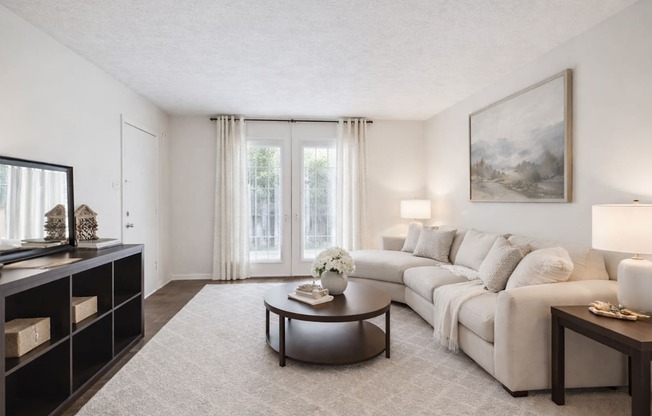 A living room with a white couch, a coffee table, and a painting on the wall.