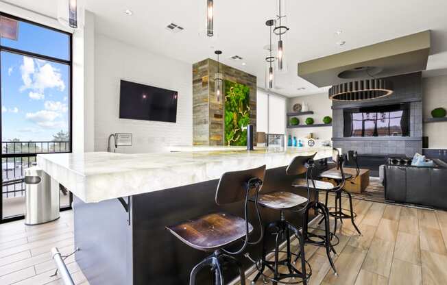 a kitchen with a long island with a marble countertop and four stools