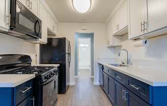 A kitchen with black appliances and blue cabinets.