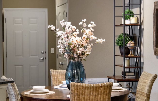 a dining room with a table and chairs and a vase of flowers in Fenwyck Manor Apartment home