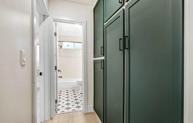 a bathroom with green doors and a toilet and a tub