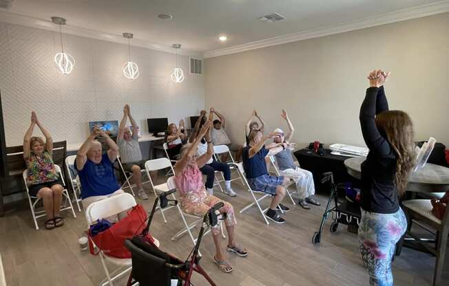 a group of people sitting in a room with their hands in the air