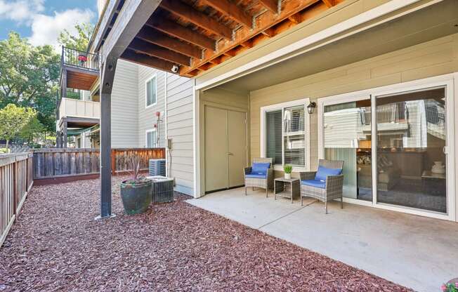 a covered patio with chairs and a sliding glass door